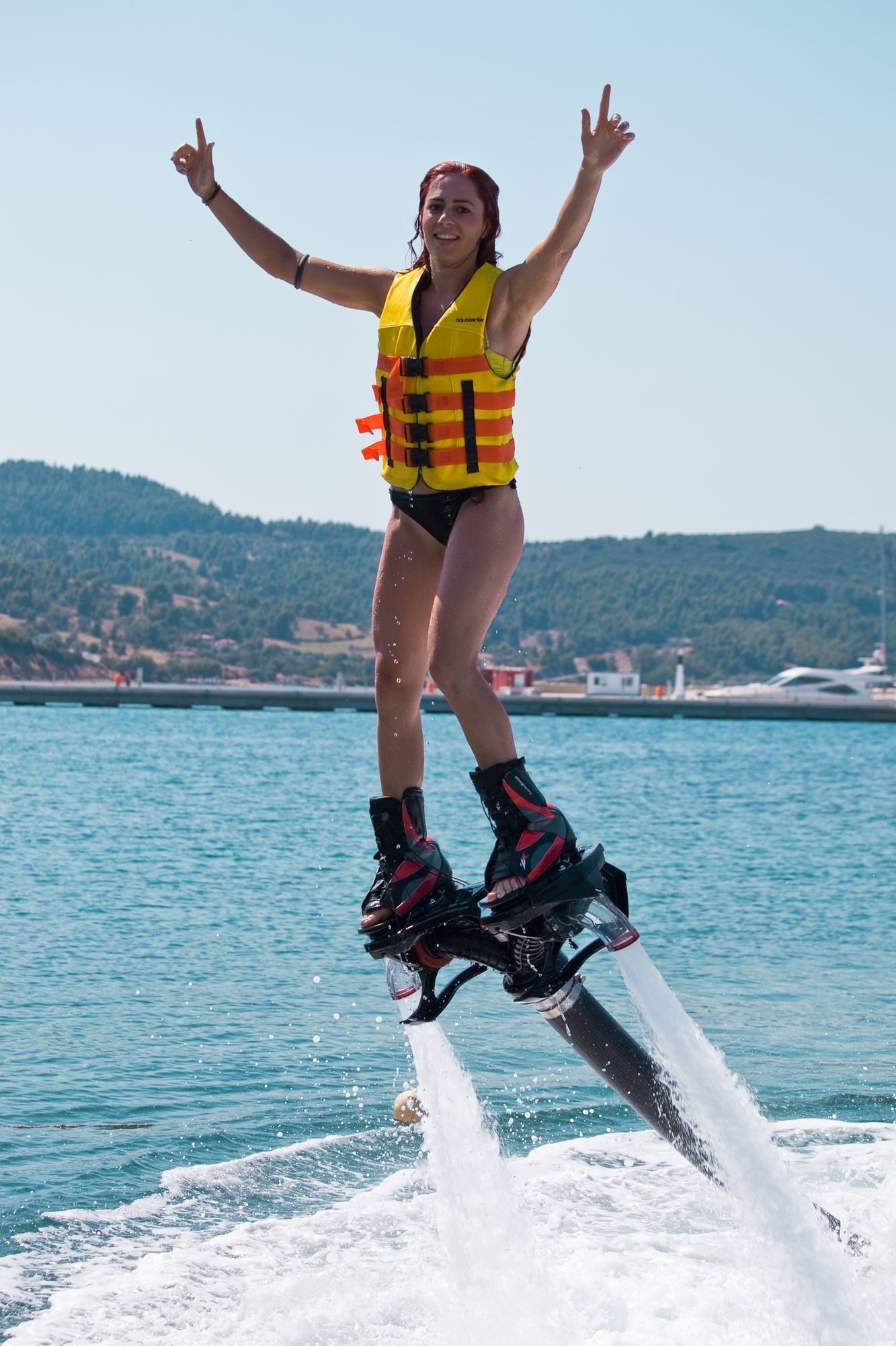 Woman enjoying flyboard water sports above the sea on a sunny day