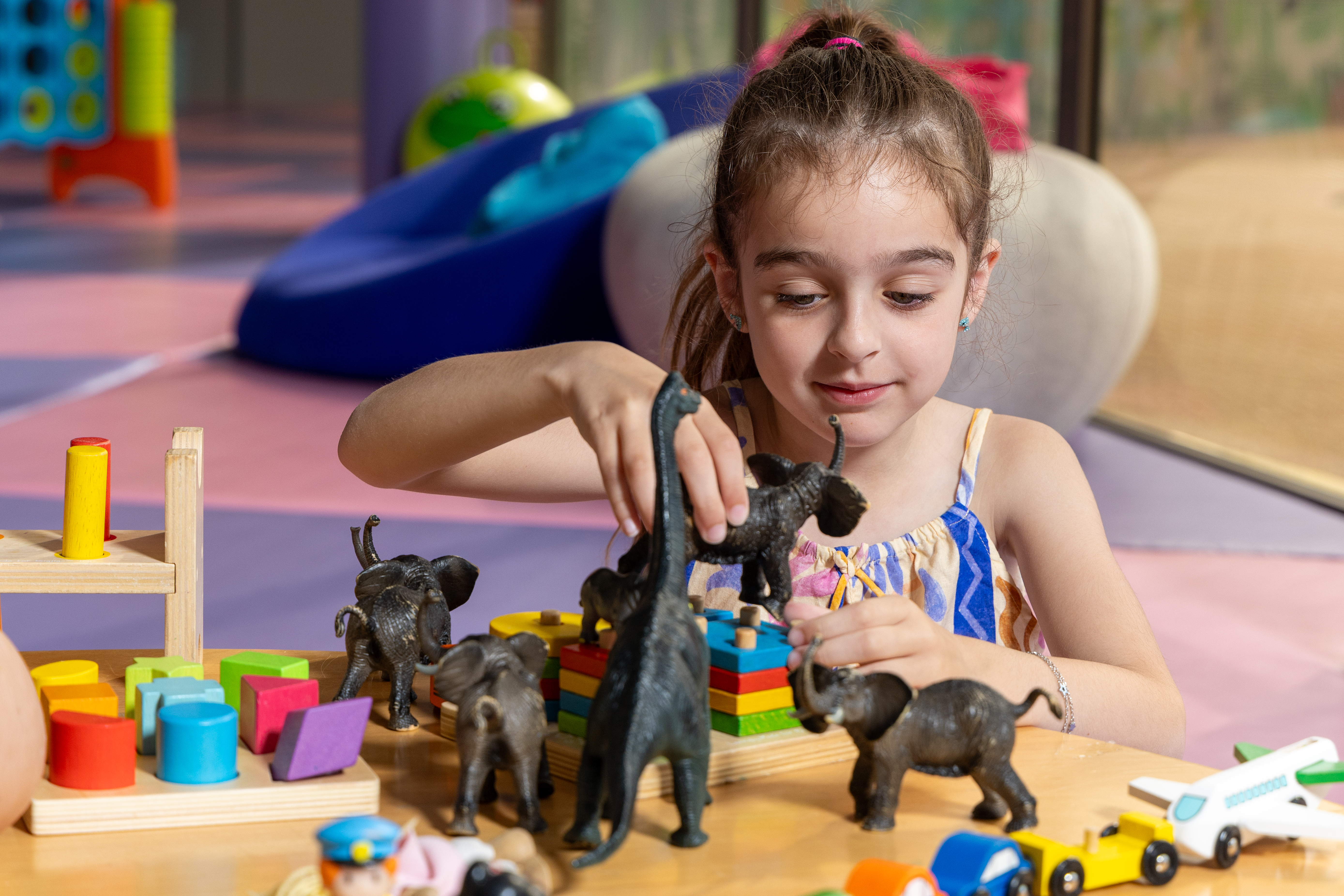 Little girl playing with toy animals and colorful blocks at the Kids Planet activity area