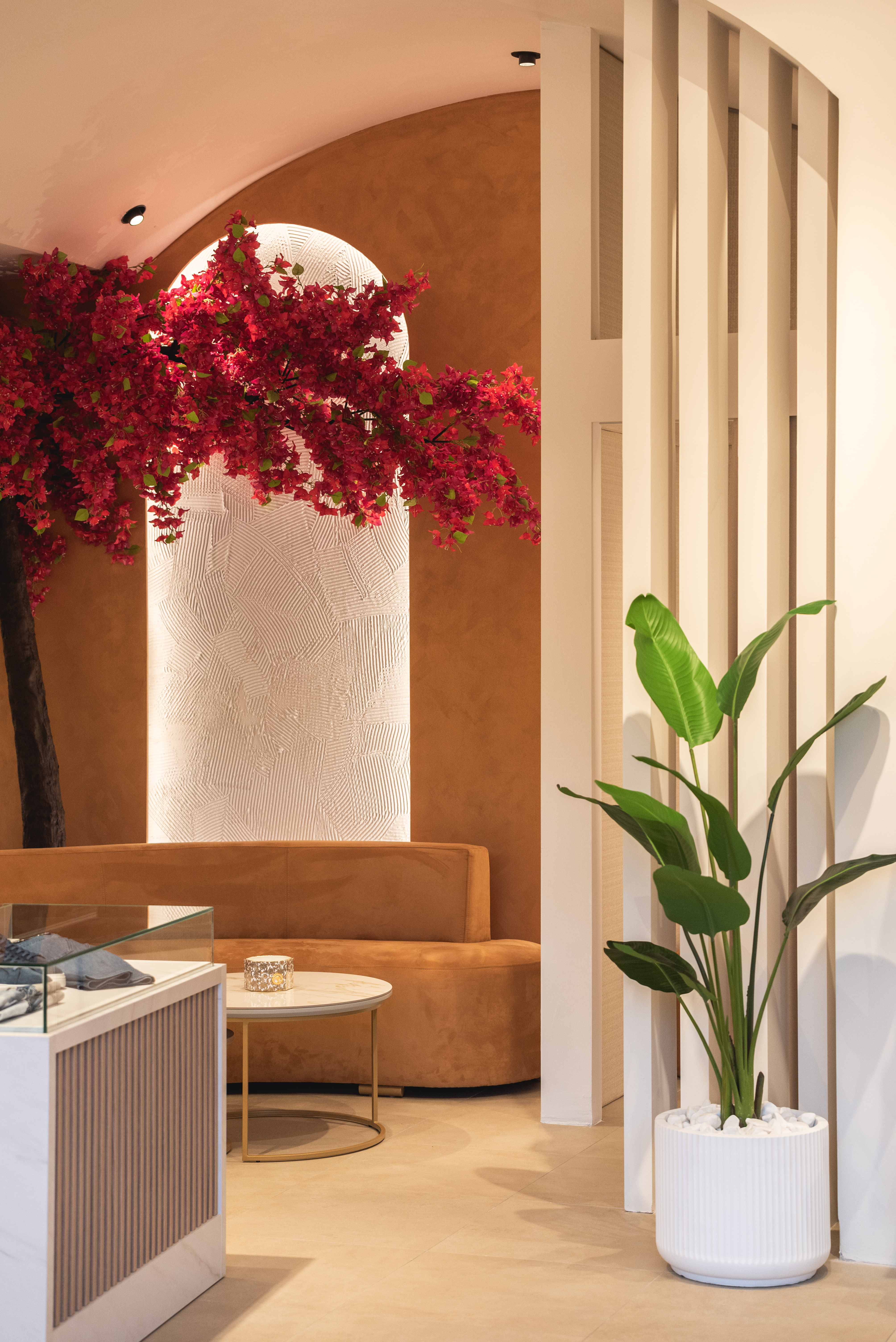 Elegant boutique interior with terracotta sofa, marble table, bougainvillea decor and potted plant
