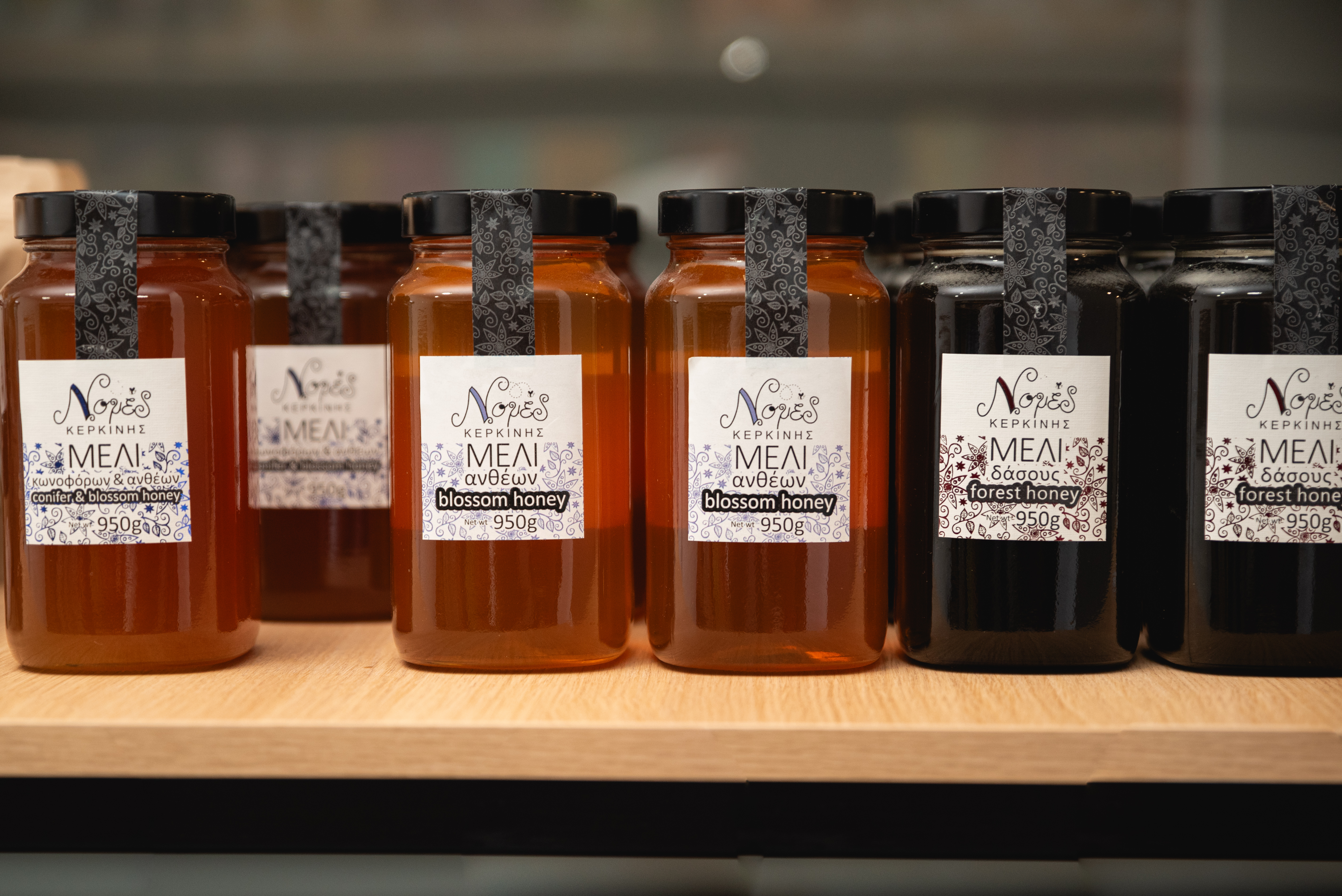 Glass jars of Greek blossom and forest honey from Kerkini, neatly displayed on a wooden shelf