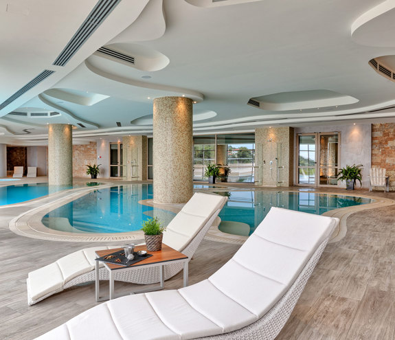 Elegant indoor spa pool with loungers, mosaic columns, and relaxing ambience