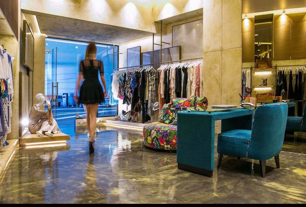 Luxury boutique with designer clothing racks and elegant decor featuring teal chairs and marble floor
