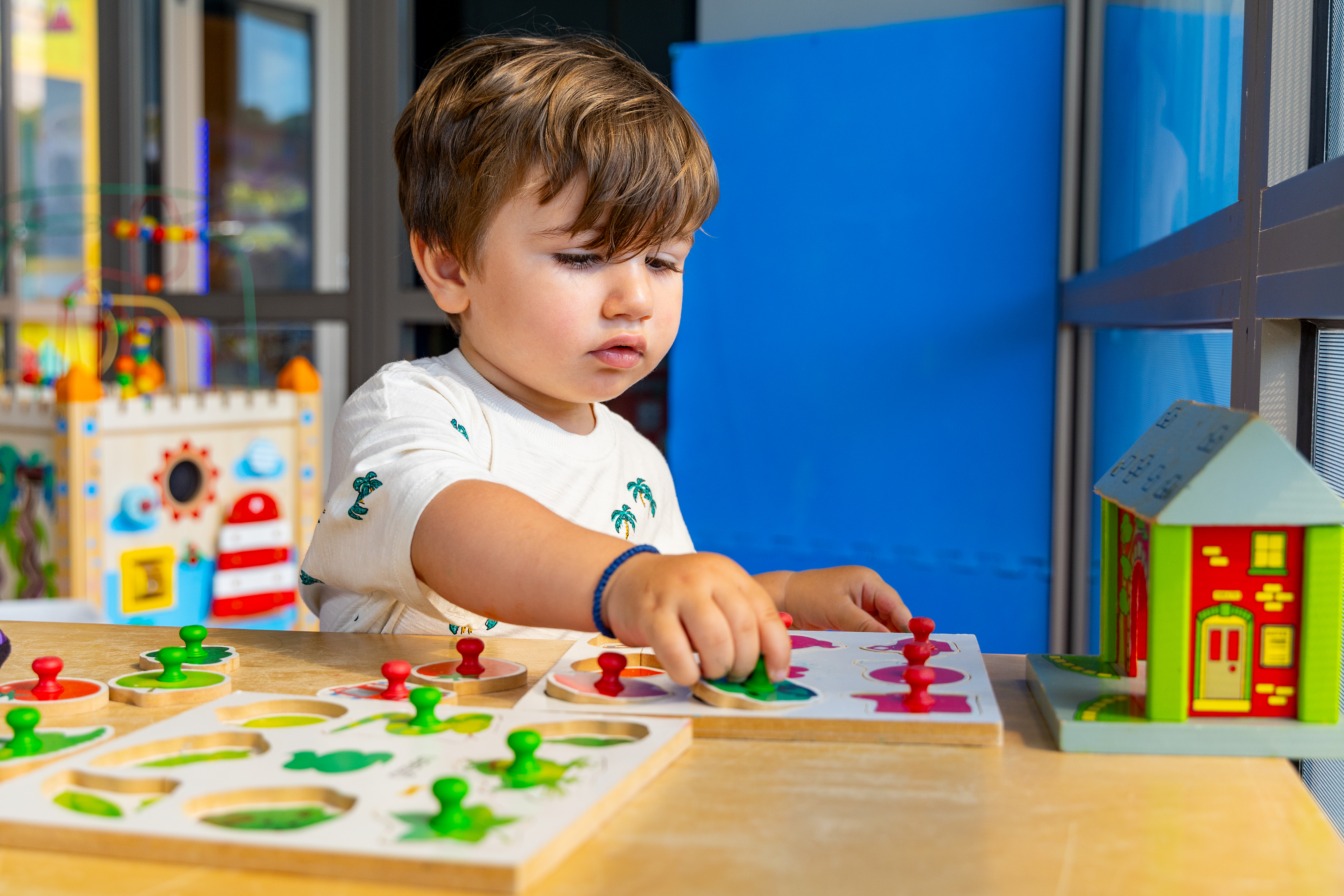 Toddler playing with wooden play and learn toys inside the indoor playground of Kids Planet