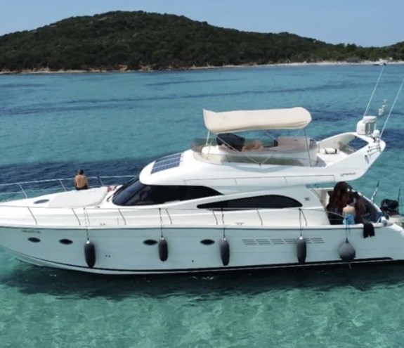 Luxurious white motor yacht anchored in crystal clear turquoise water with guests relaxing on deck