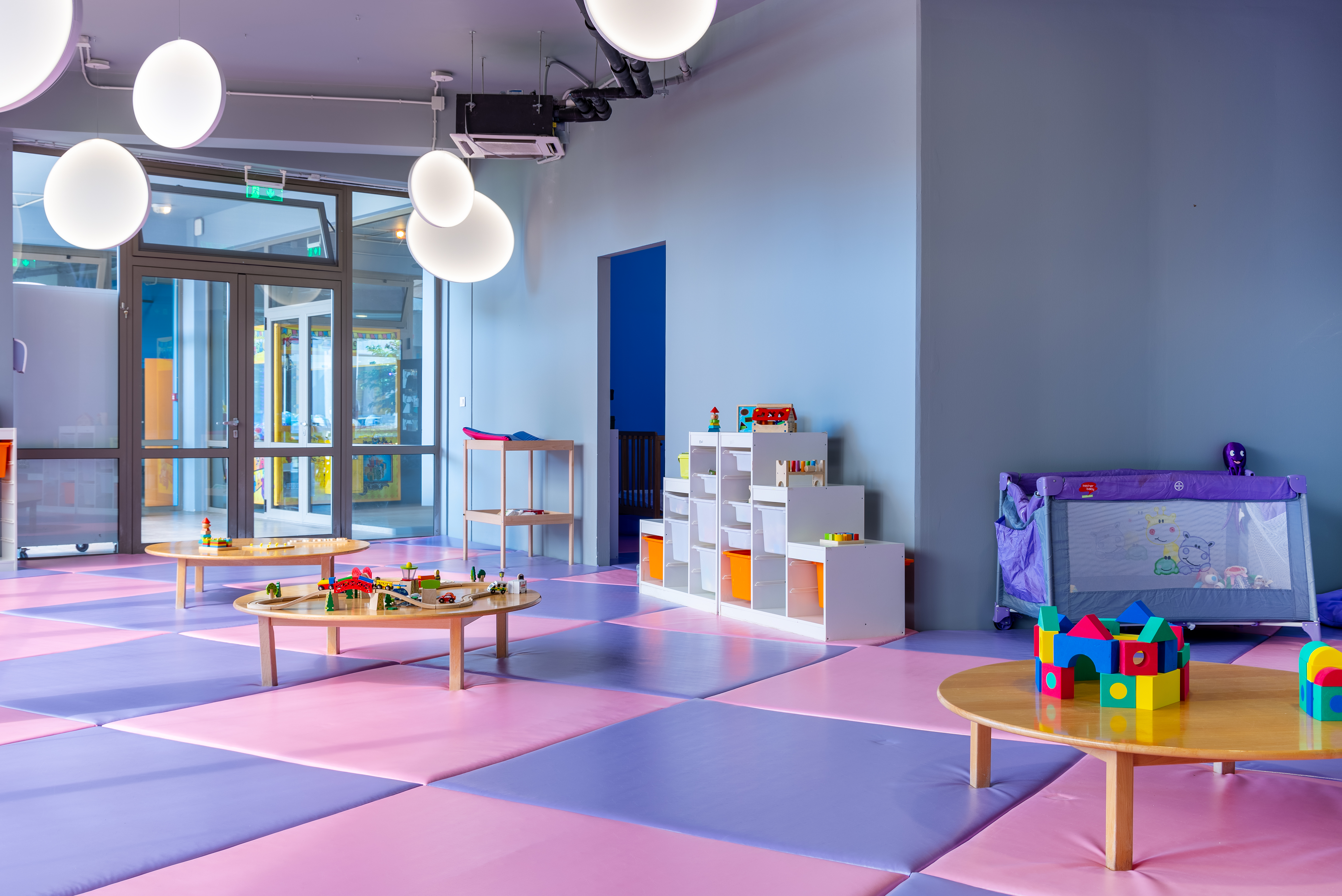 Colorful indoor kids' playroom with activity tables, toys, and soft mats at Kids Planet